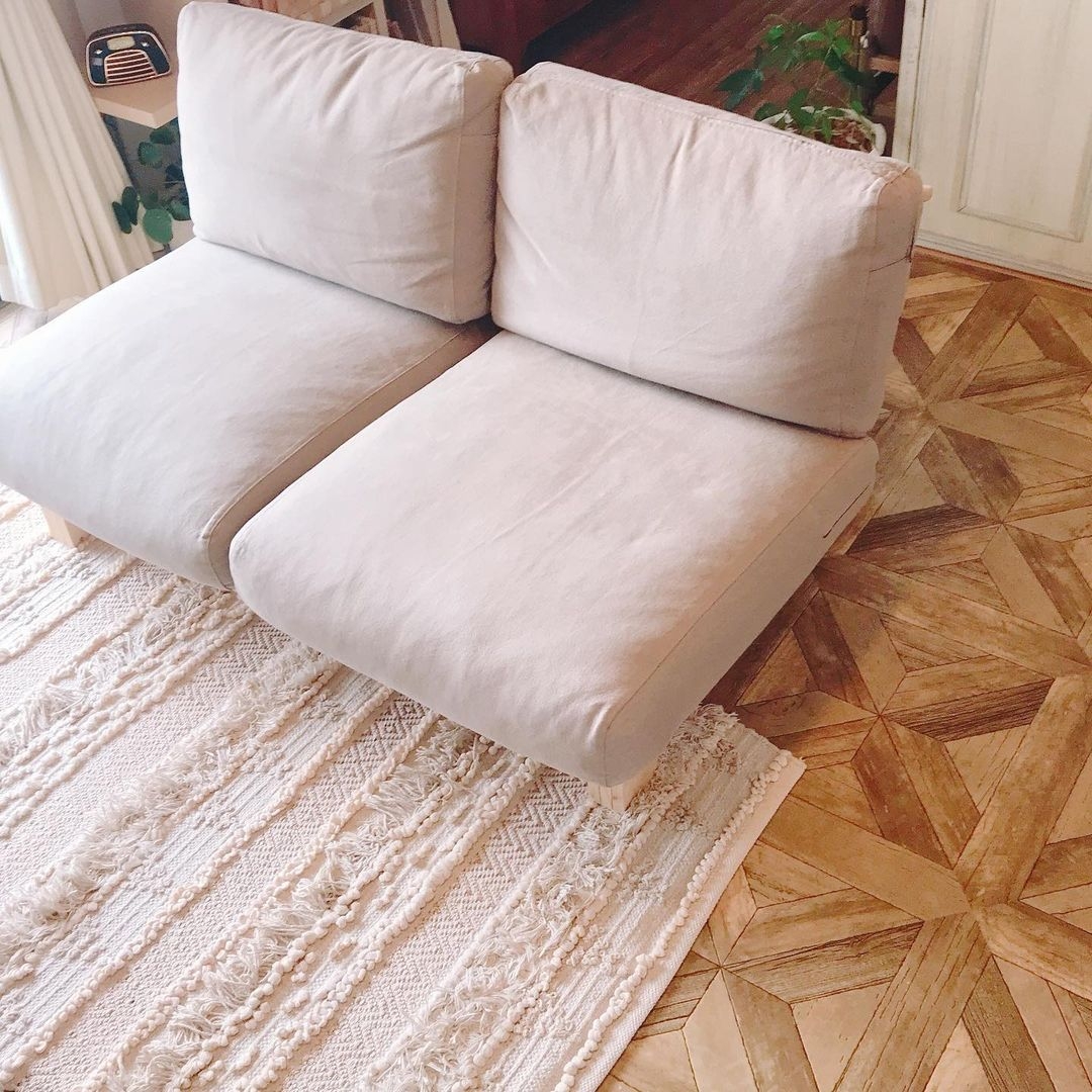 パーケット柄のクッションフロアをリビングに敷いた実例。ベージュのソファやアイボリーラグと調和し、ナチュラルで上品な雰囲気に仕上がっている。