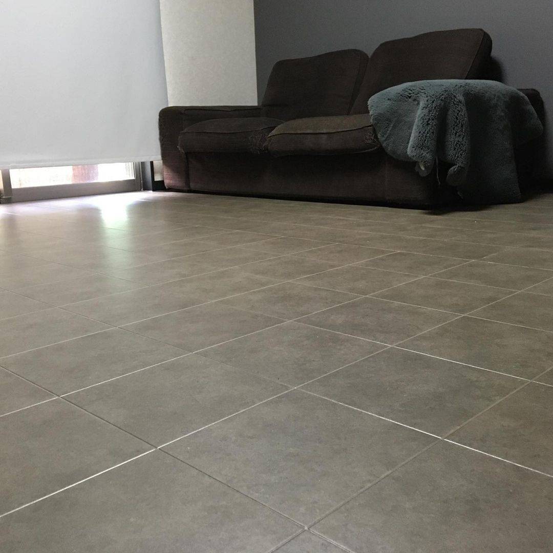 グレーの石目柄クッションフロアをリビングに敷いた実例。シックな雰囲気のソファと調和し、落ち着いた大人の空間に仕上がっている。