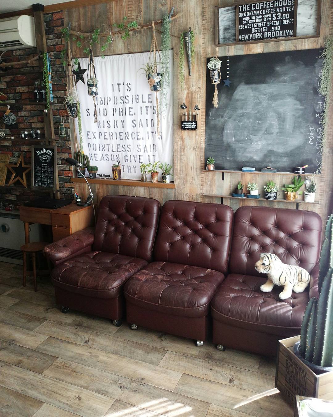 古材調のクッションフロアをリビングに敷いた実例。レンガ調の壁やレザーソファと組み合わせて、ヴィンテージ感あふれるインテリアに仕上がっている。