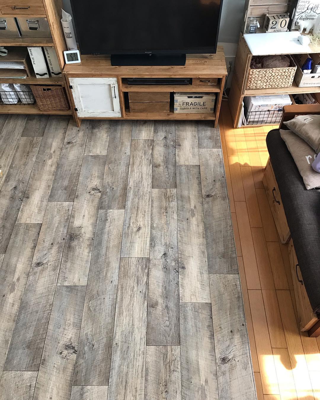 古材調のクッションフロアをリビングに敷いた実例。テレビボードや収納家具と調和し、落ち着いたヴィンテージ感のある空間に仕上がっている。