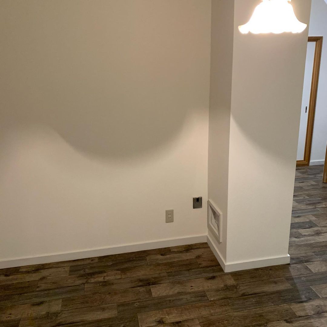 古材調のクッションフロアをリビングに敷いた実例。深みのある色合いが白い壁に映え、落ち着いた雰囲気をつくり出している。