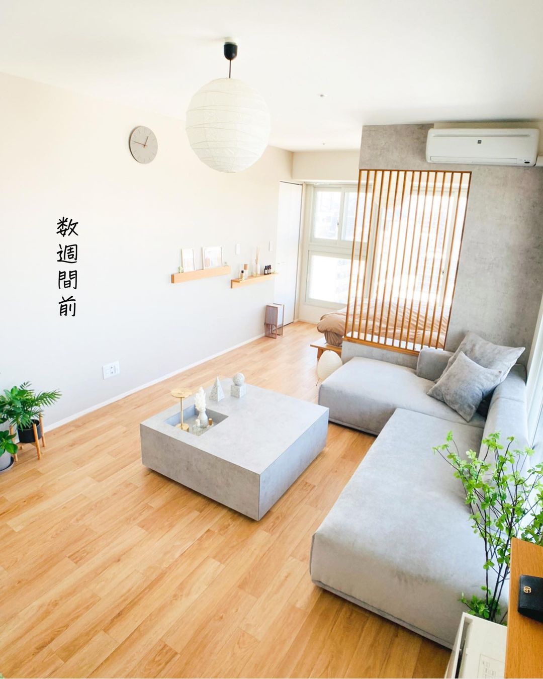 木目柄のクッションフロアを敷いたリビング。明るいトーンの床がグレーのソファやコンクリート調のテーブルと調和し、ナチュラルモダンな印象に仕上がっている。