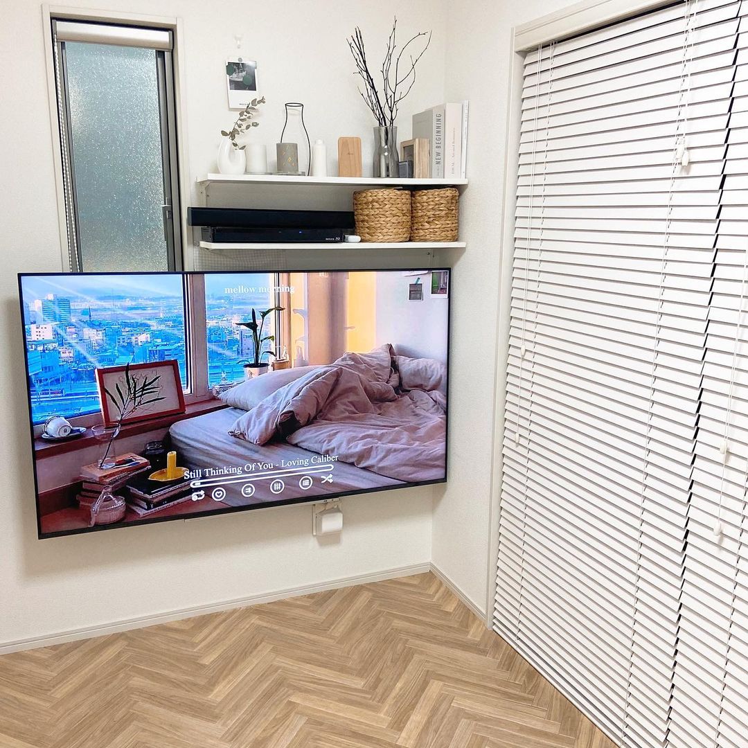 ヘリンボーン柄のクッションフロアを敷いたリビング。ナチュラルな木目がテレビまわりの白い壁やブラインドと調和し、洗練された北欧テイストの空間になっている。