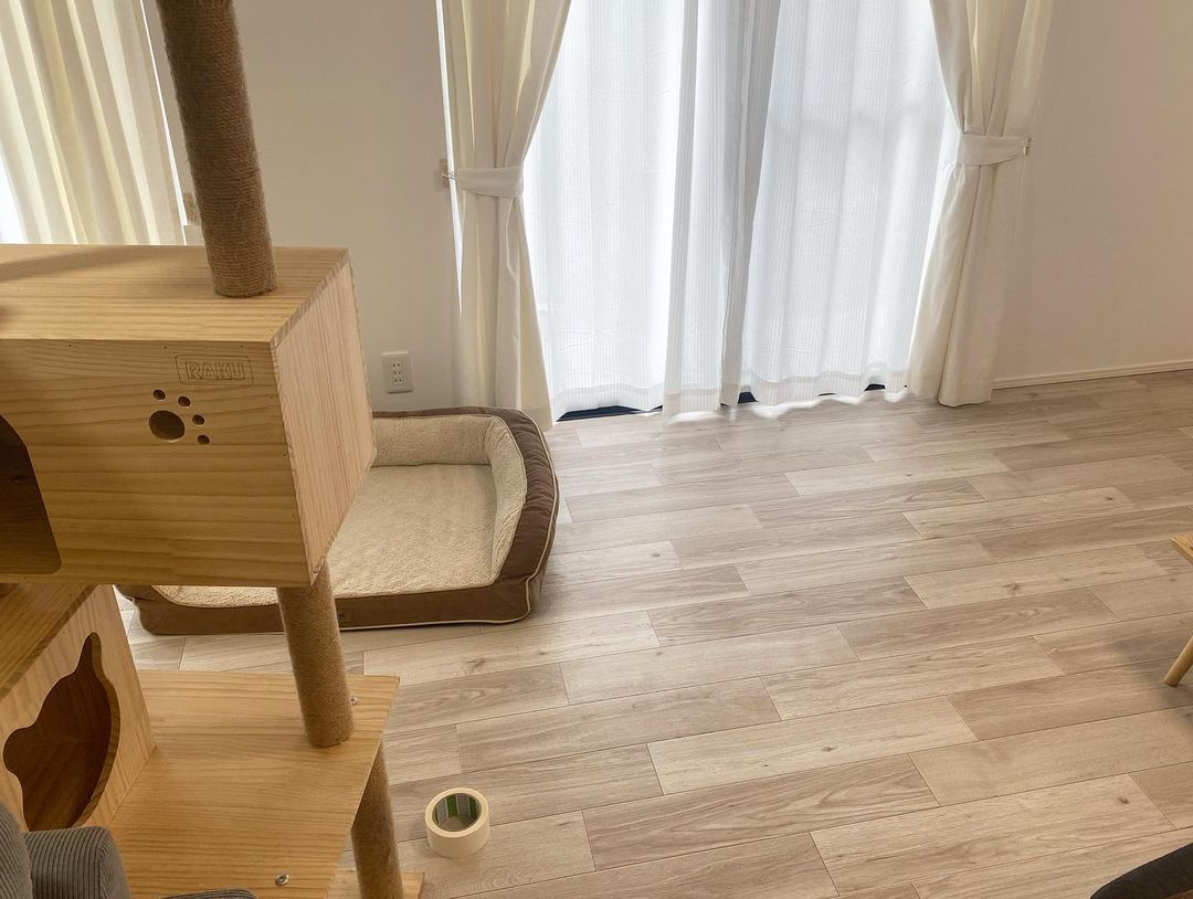 ナチュラルな木目柄クッションフロアをリビングに敷いた実例。ペット用のキャットタワーやベッドと自然になじみ、清潔感とあたたかみのある空間になっている。