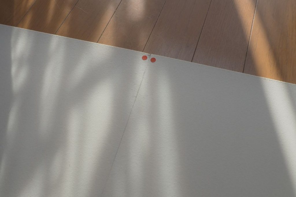 ラグリエのペットマット裏面の丸シール。柄が合うように、マットの向きを確認しながらDIYで簡単に設置できる様子。