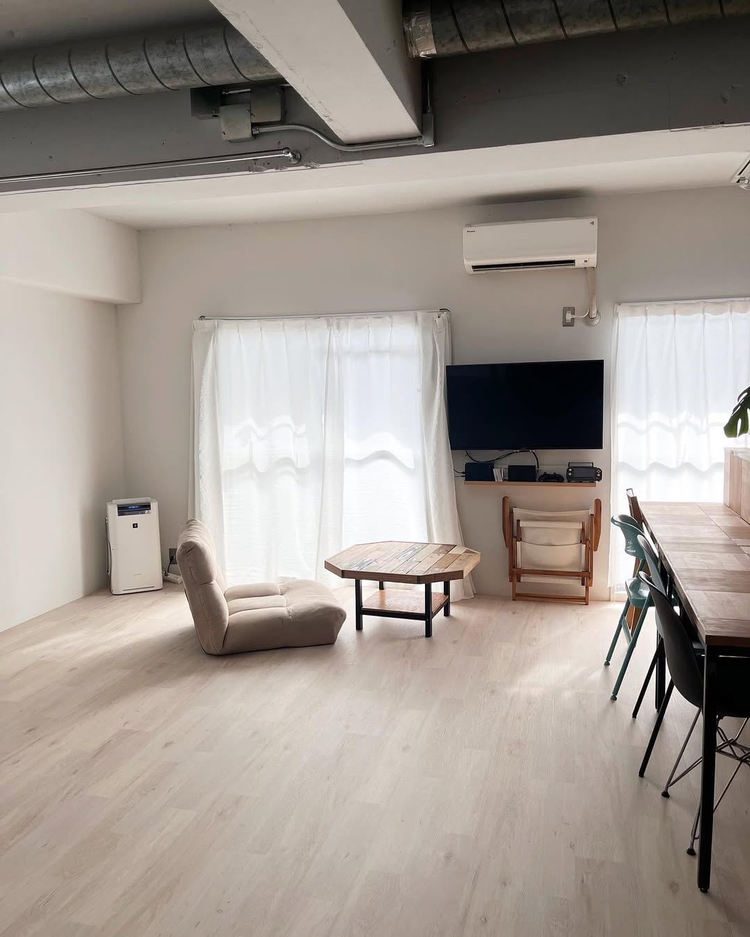 ホワイトウッド調のクッションフロアを敷いたリビング。シンプルな家具と白いカーテンが調和し、明るく開放感のある雰囲気を演出している。