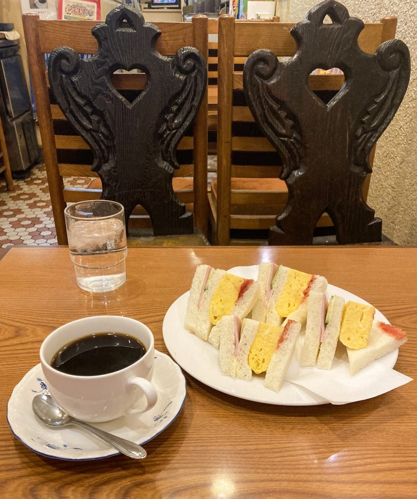 池田屋珈琲の人気メニュー、厚焼き玉子入りサンドイッチとブレンドコーヒーのモーニングセット|レトロな喫茶店のテーブル席風景