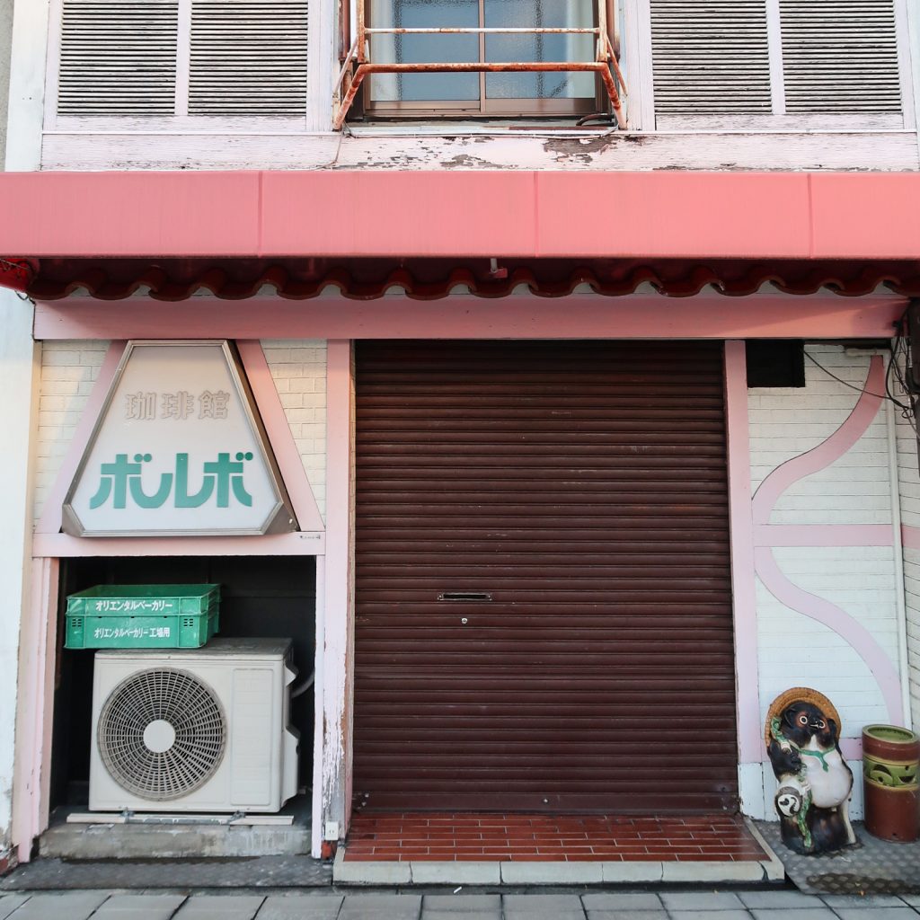 ピンクの外観と茶色のシャッターが印象的な『珈琲館ボルボ』の店構え|昭和レトロな雰囲気が残る閉店後の喫茶店