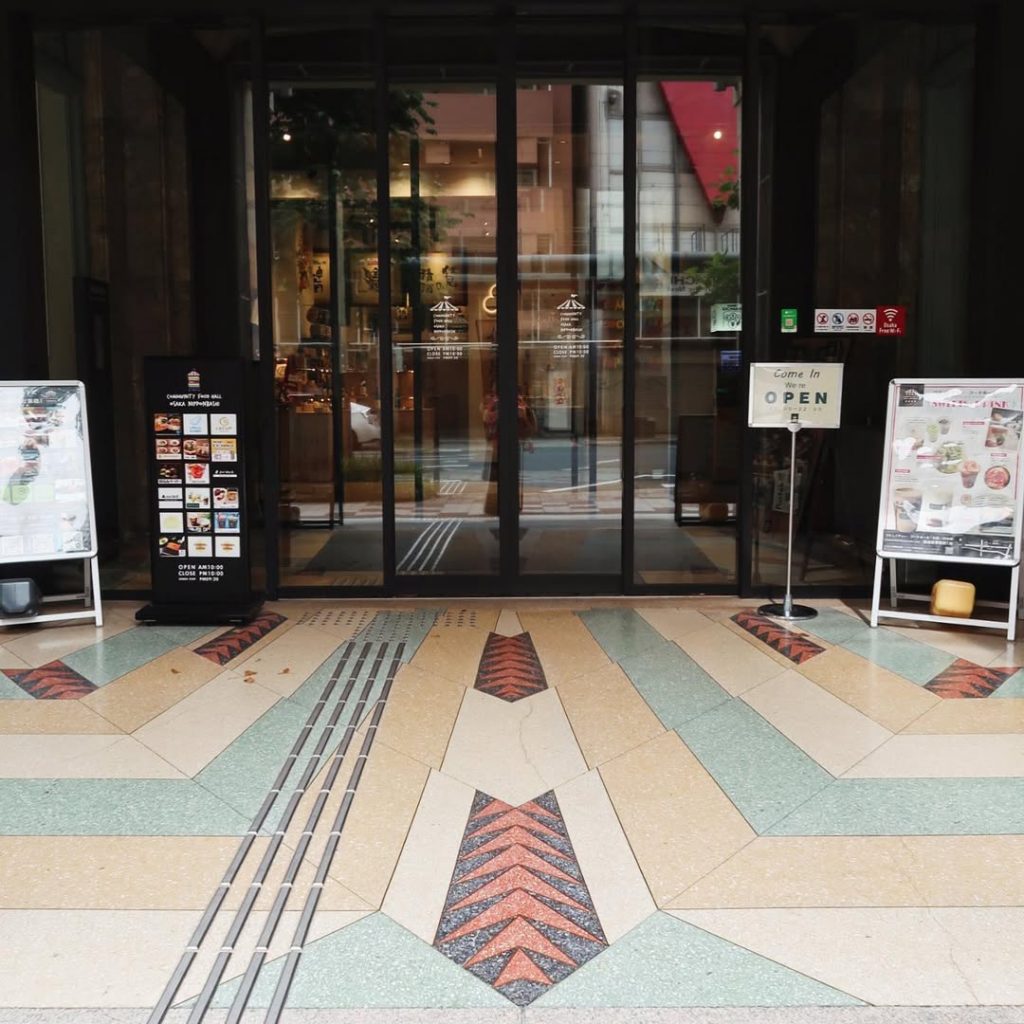 高島屋東別館のエントランス前に広がる幾何学模様のテラゾー床|赤いアカンサス模様がアクセント