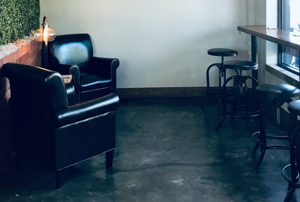 重厚感のある革張りチェアとモルタル風の床が調和するカフェ風インテリア。落ち着いた空間に映えるインダストリアルスタイル