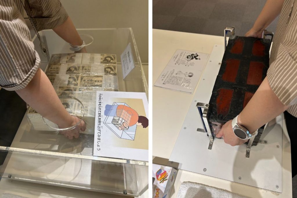 岡崎信用金庫資料館の体験展示コーナーで1億円の重さと千両箱の重さを体験している様子