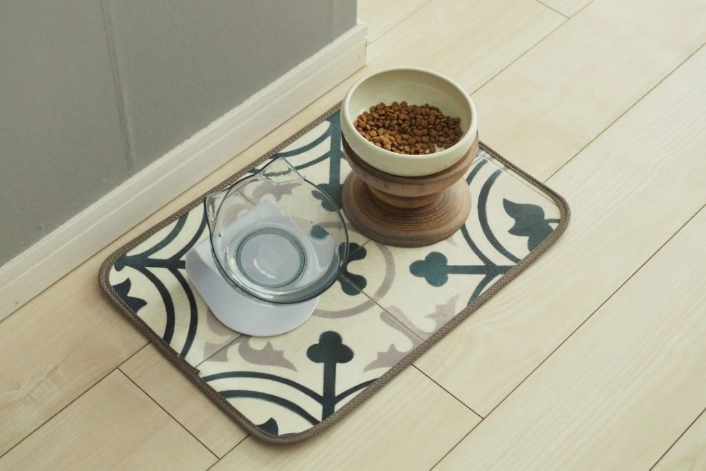 ラグリエのペット用食事マット「mogmog」モロッカン柄。木製スタンドにフードボウルとガラス製の水入れを置いたナチュラルな食事スペース。