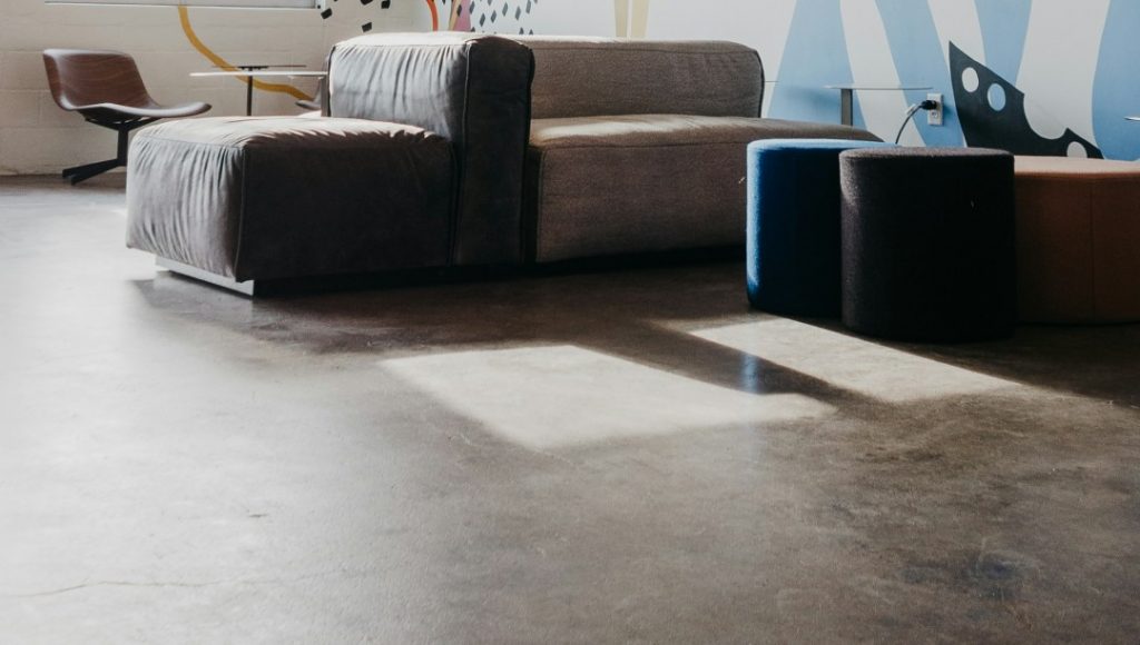 日差しが差し込むリビングのコンクリート調クッションフロア。乾燥した冬は帯電しやすく、静電気によるホコリの付着が気になる空間。
