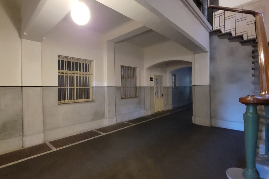 名古屋市市政資料館の地下廊下。灰色の壁とアーチ構造が特徴で、ひんやりした空気が漂う静かな通路。