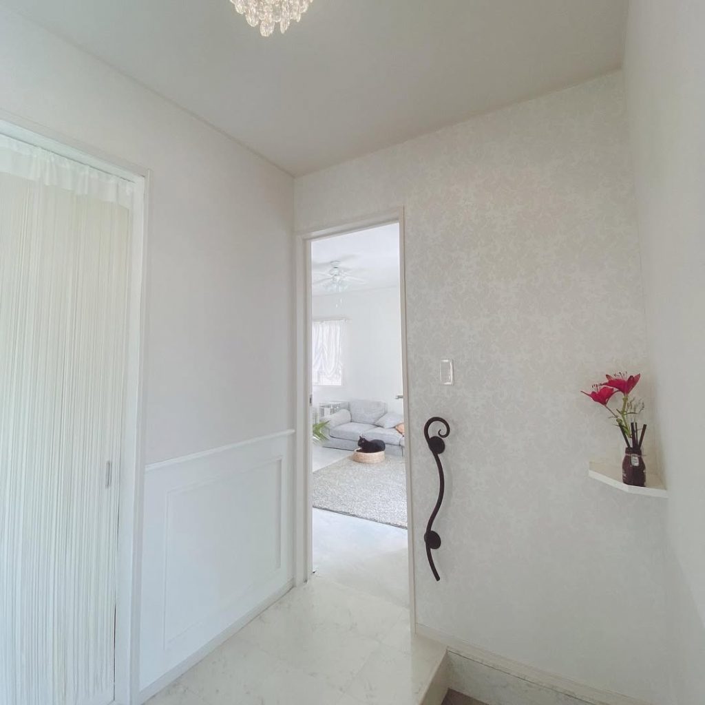 大理石調の床と白い壁でまとめられた玄関から、奥のリビングへ続く明るい空間。上品で統一感のあるインテリアが特徴的な実例。