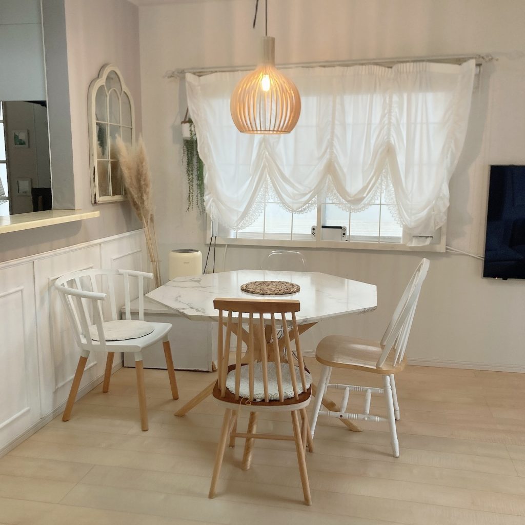 ベージュのフローリングと白を基調としたチェアやカーテンが調和したダイニング。丸みのある照明がアクセントになったやさしい印象の空間。