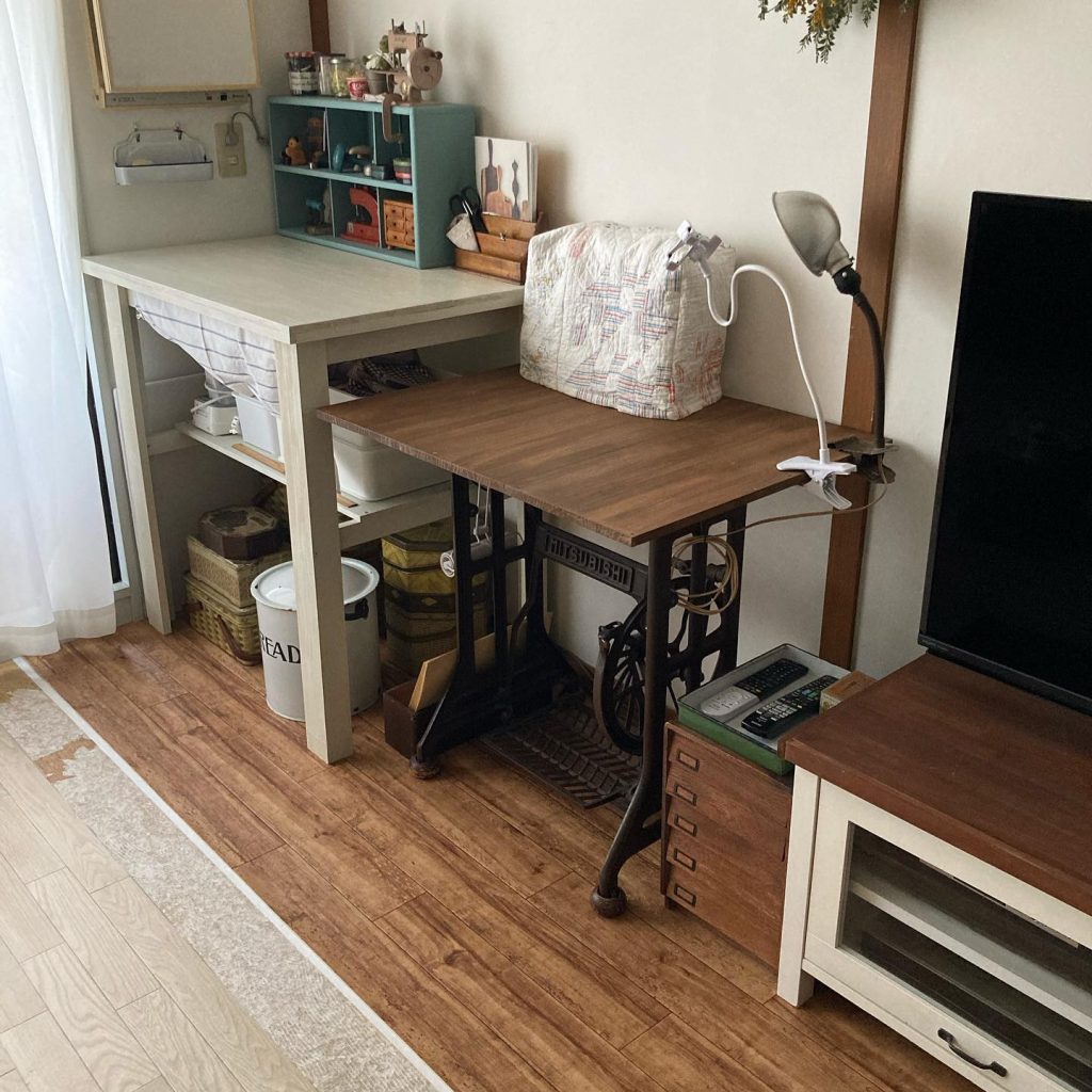 クッションフロアを敷いた部屋の一角に、作業台やアンティーク調ミシン台が配置されているワークスペースの写真。