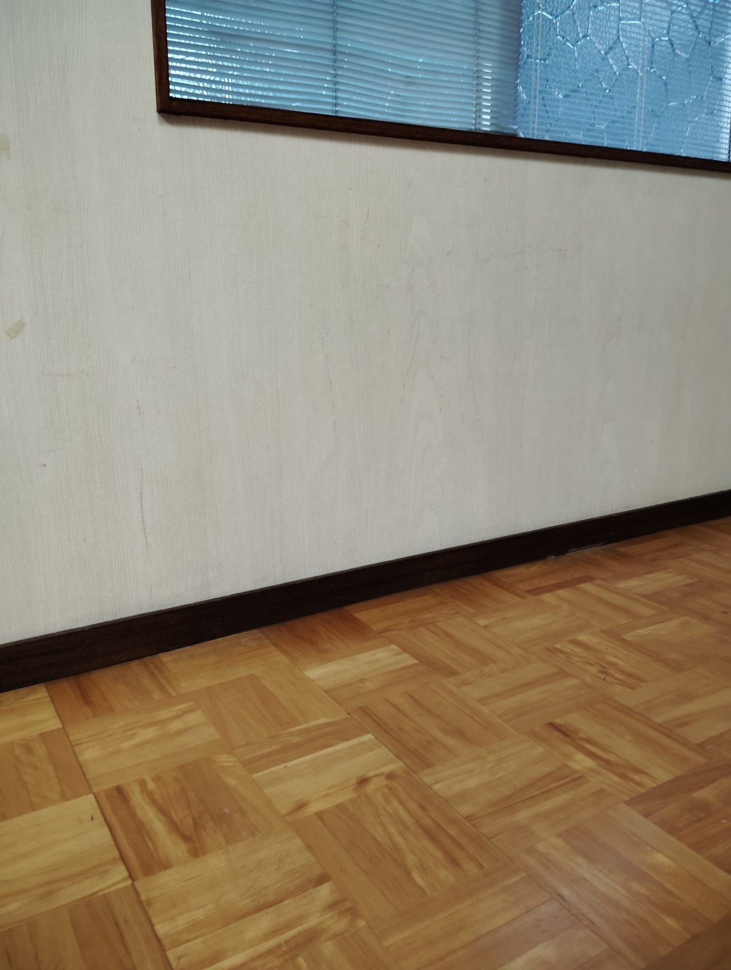 賃貸の一室にある既存のフローリング。木目が濃く、キッズスペースをつくる前の床の状態。