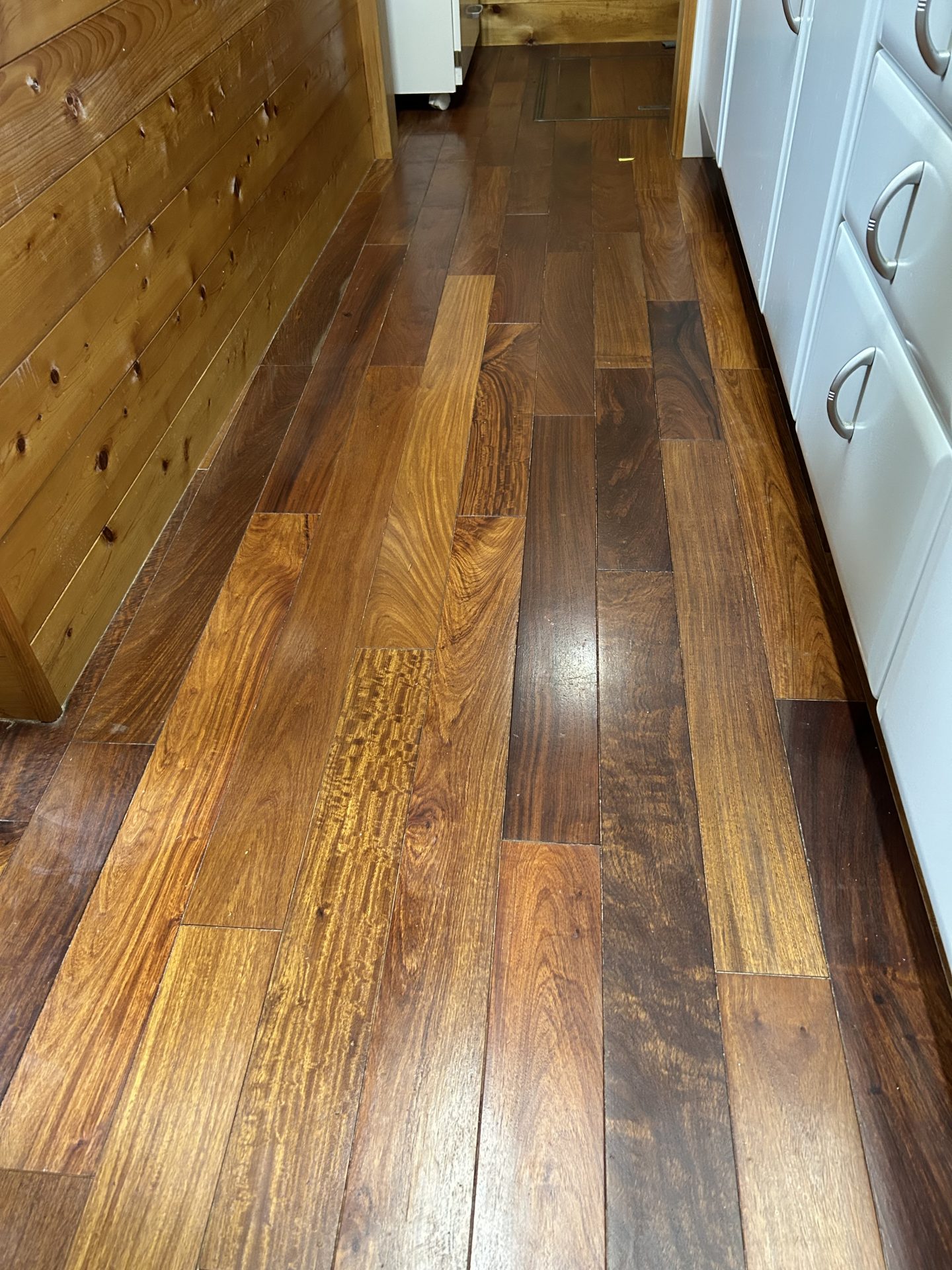 キッチンに敷かれた既存のフローリング。冬場に底冷えしやすく、印象がやや暗めの木目。