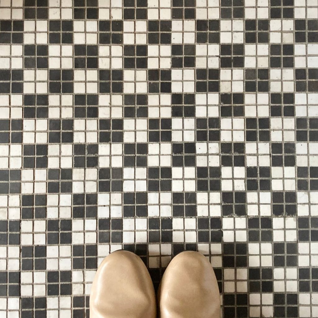 旅館 橋本の香の水まわりに残るモノトーンのモザイクタイル床。黒と白の小さなタイルが市松のように配置されたデザイン。