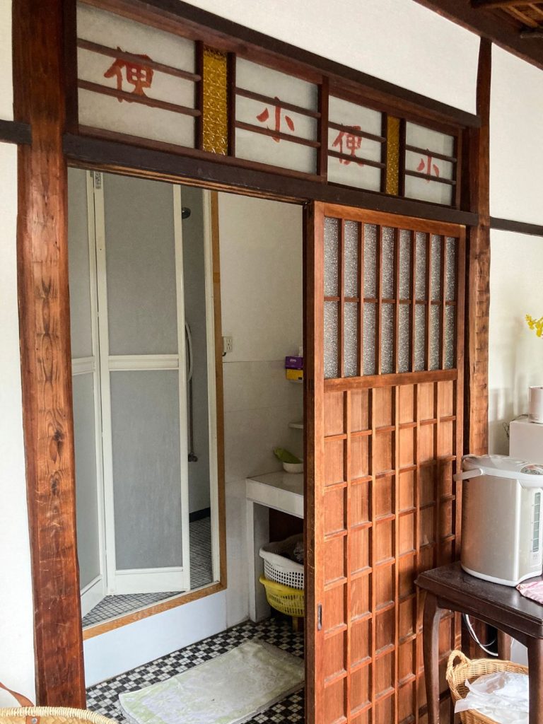 旅館 橋本の香の水まわり空間。『小便』と書かれた欄間ガラスと木製引き戸が残り、奥にはモザイクタイル床の洗面・浴室が見える。