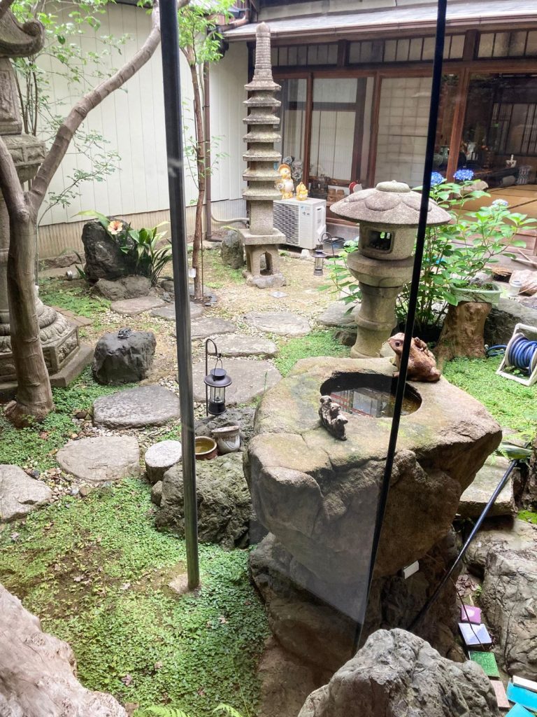 旅館 橋本の香の中庭。石灯籠や石塔、苔むした大きな石が配置された静かな日本庭園が建物に囲まれて広がる。