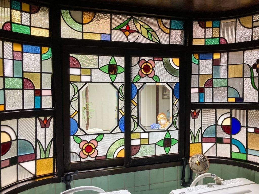 旅館 橋本の香の1階にある出窓のステンドグラス。アールデコ調の花柄や幾何学模様を組み合わせた色彩豊かなガラス装飾。