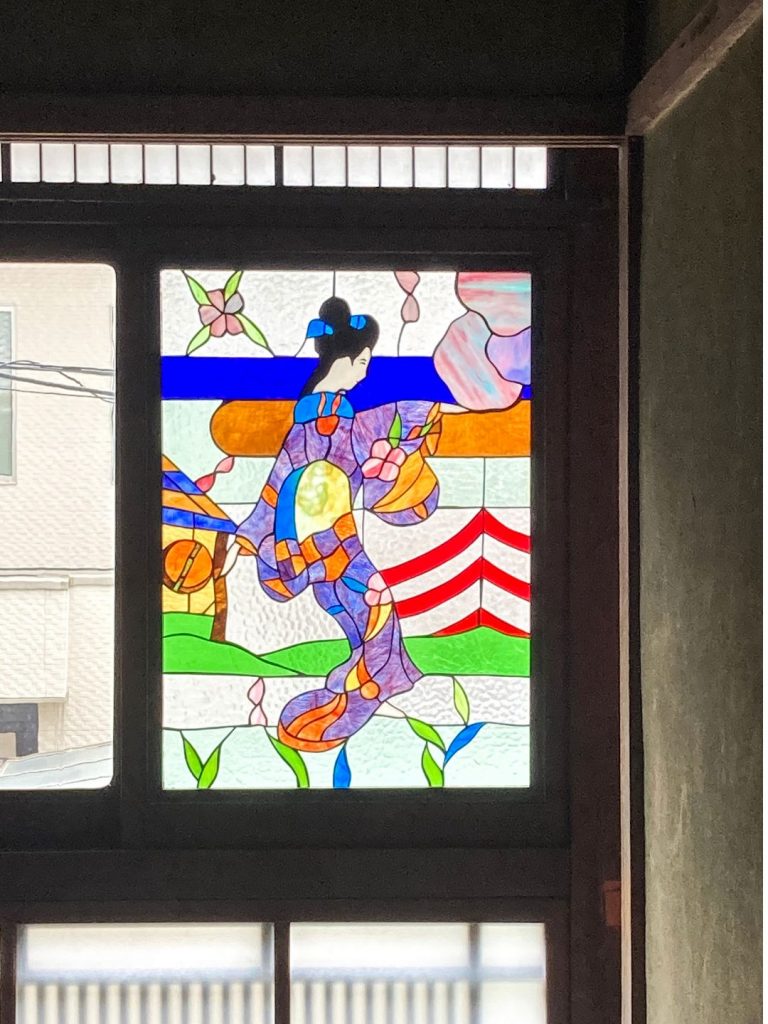 旧加島楼の2階に残る、着物姿の女性を描いた色鮮やかなステンドグラス。
