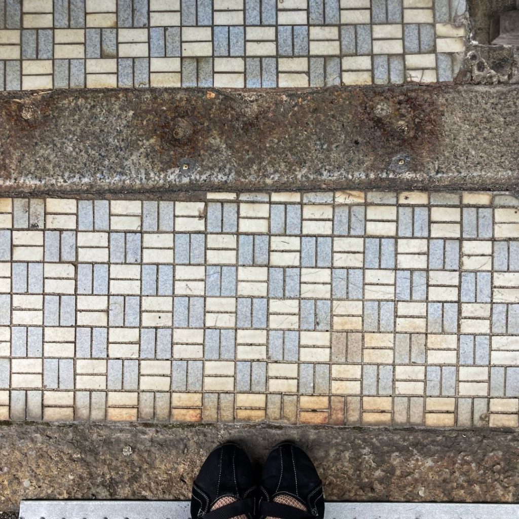 洋食店やをりきの入口に敷かれた細かな矩形タイル床。淡いブルーとベージュを組み合わせた上品なデザインが特徴。