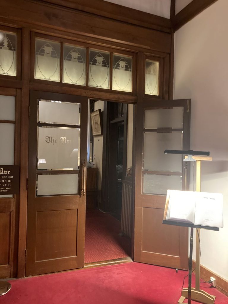 今井晶子の床旅で訪れた奈良ホテルのバー入口。木製の扉とすりガラス、赤いカーペットが印象的なクラシカルな空間。