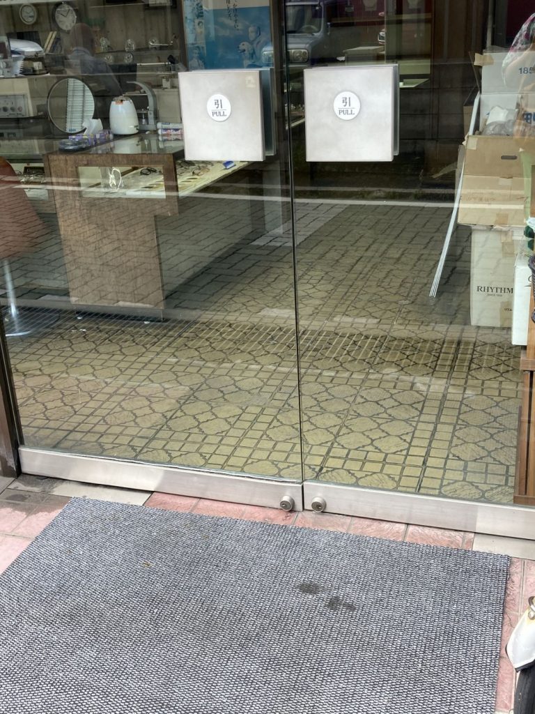 大和郡山商店街の店舗外観。ガラス扉越しに、幾何学模様が連続するタイル柄の床が見える様子。
