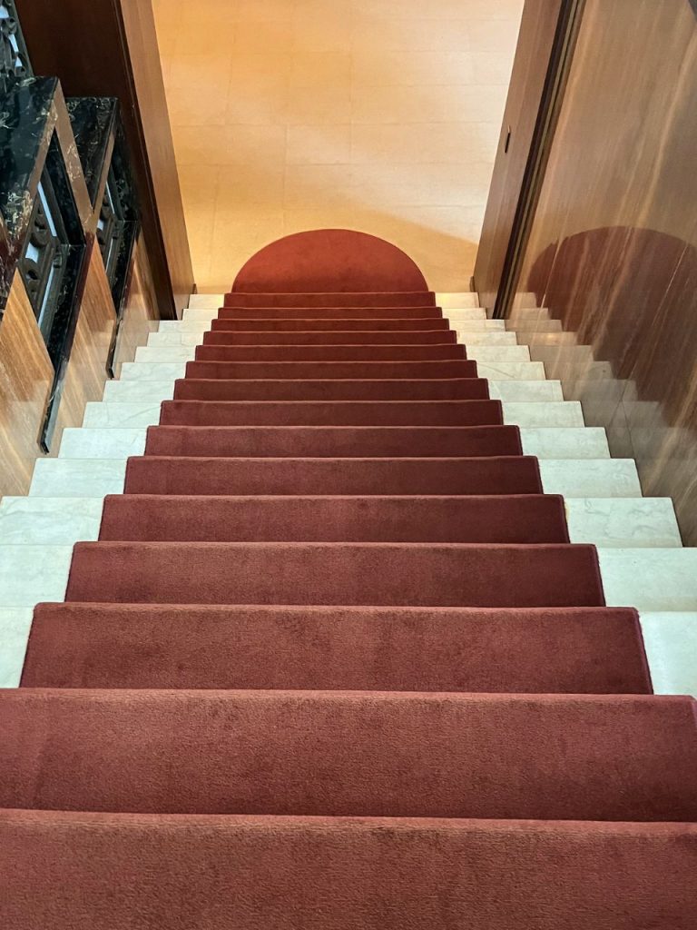 東京都庭園美術館（旧朝香宮邸）の階段室にある赤いカーペット敷きの直線階段と白い大理石の踏み面