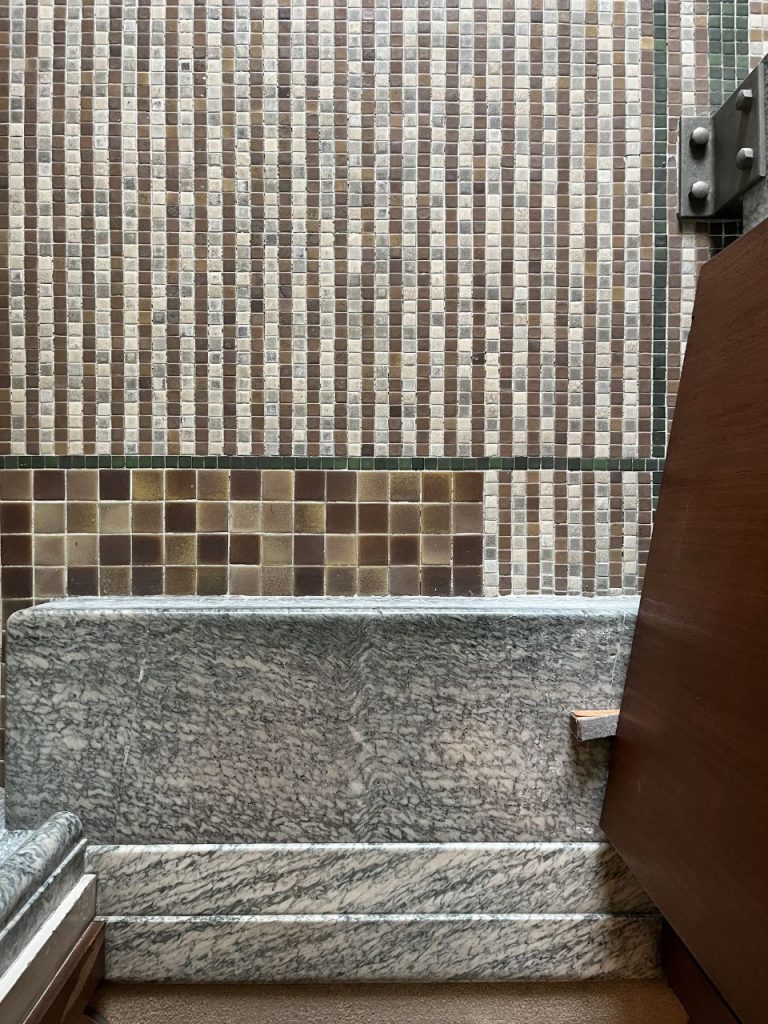 旧朝香宮邸の浴室の一角。大理石の腰壁と茶系のモザイクタイル壁、浴槽まわりのディテール