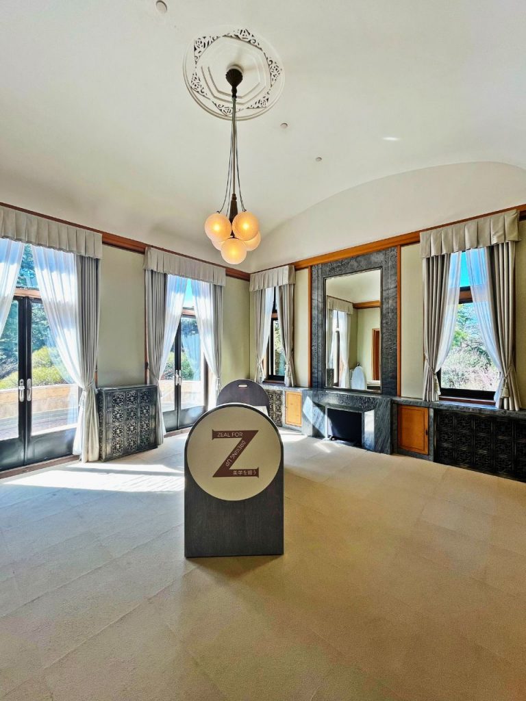 旧朝香宮邸の広間。アールを描く天井と丸いペンダント照明、大きな窓と暖炉が配された空間