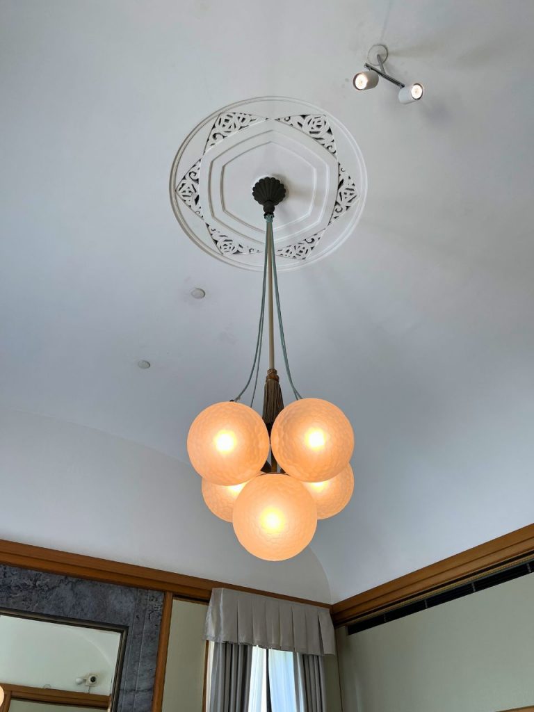 旧朝香宮邸の天井装飾と球体ガラスのペンダント照明。幾何学模様のレリーフと柔らかな光が広がる空間