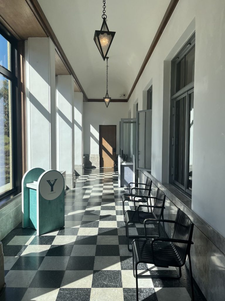 旧朝香宮邸の回廊。白壁と大きな窓に沿って黒白の市松模様タイルが続く床と三角形のペンダント照明