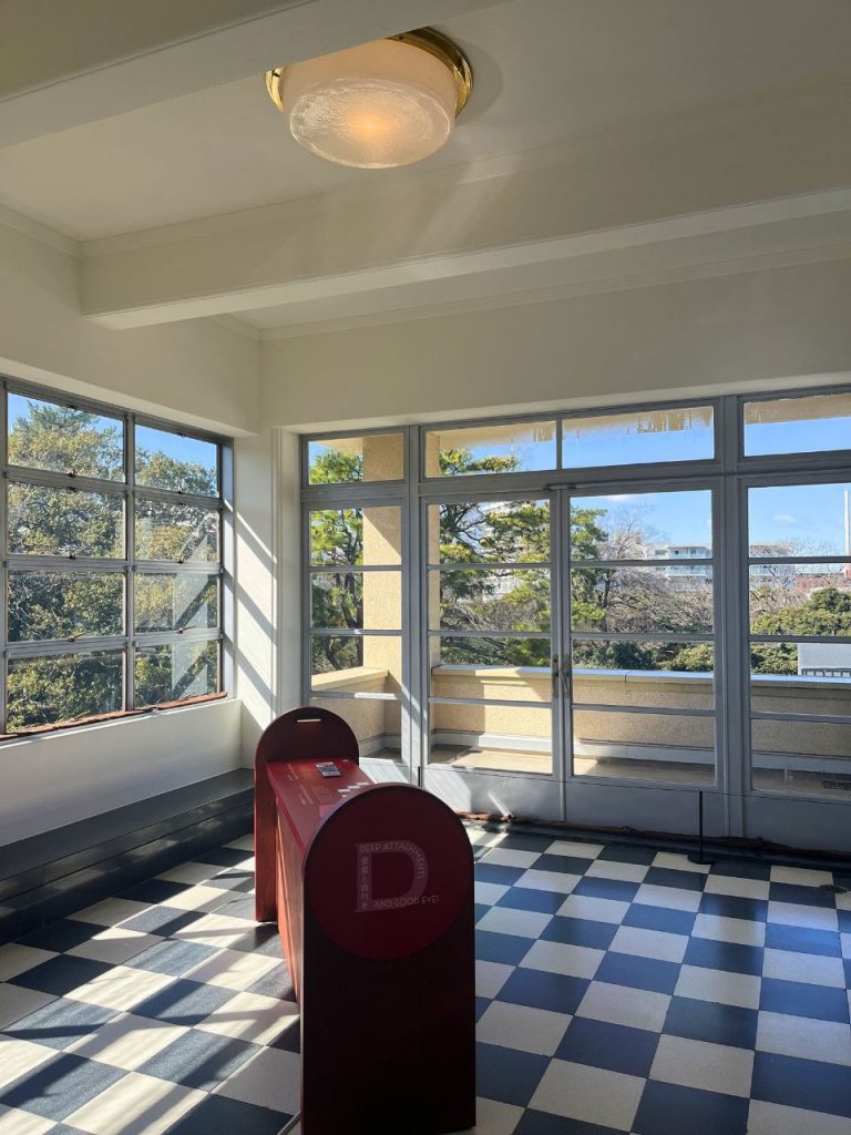 旧朝香宮邸の室内。大きな窓から庭園を望む空間に、黒白の市松模様タイル床が広がる