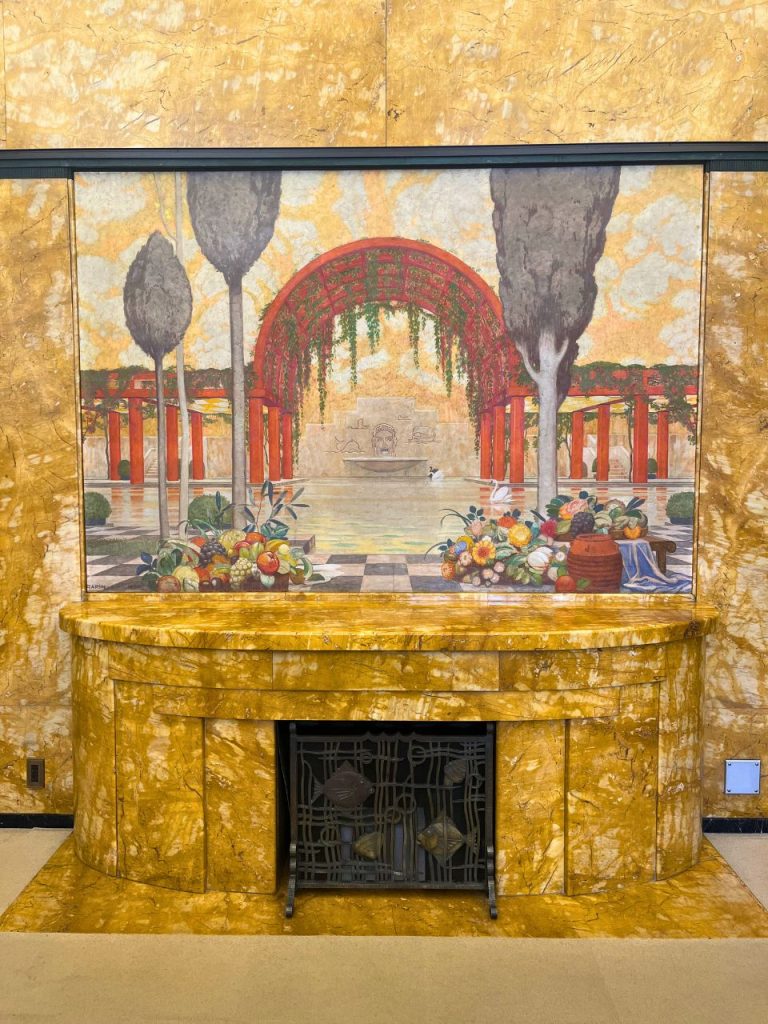 東京都庭園美術館の食堂暖炉正面。黄褐色の大理石暖炉と庭園を描いた装飾壁画。