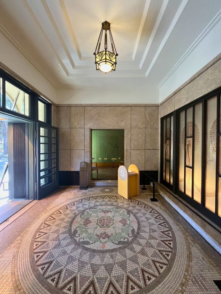 東京都庭園美術館の玄関ホール床。植物モチーフを配した円形のモザイクタイルと幾何学模様の縁取り。