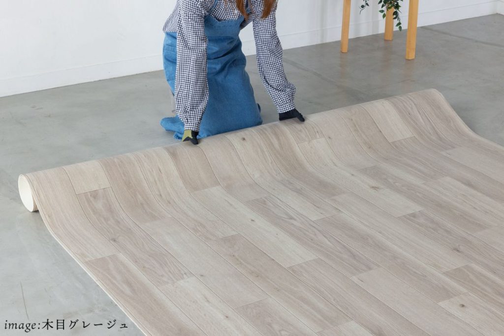 ラグリエの敷き詰め江戸間シリーズ木目グレージュを床に広げている様子。ロール状のフロアマットを並べて敷く床DIYイメージ。