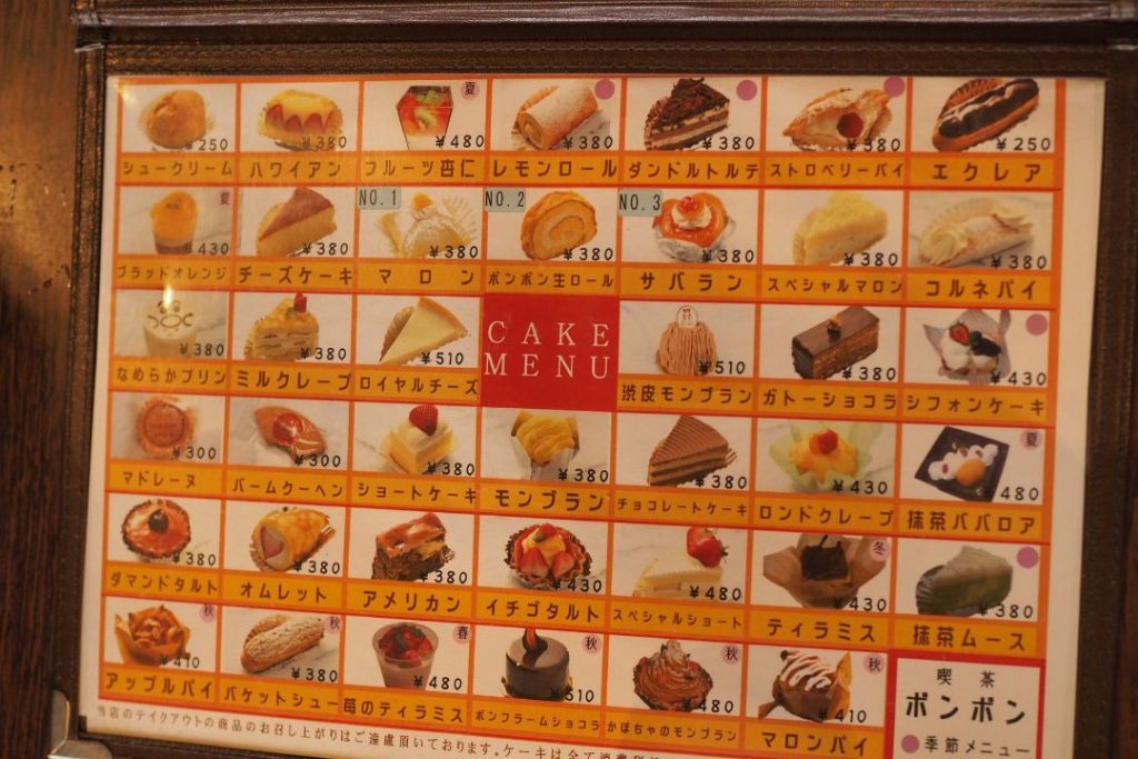 洋菓子・喫茶ボンボンのケーキメニュー。ショートケーキやエクレア、プリンなど、昔ながらの洋菓子が写真付きで並ぶメニューボード。