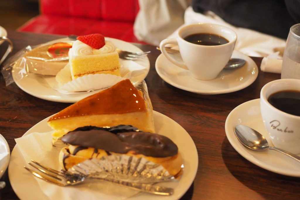洋菓子・喫茶ボンボンでいただいたケーキとコーヒー。エクレアやチーズケーキ、ショートケーキなどがテーブルに並ぶ喫茶時間。