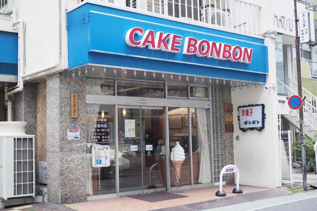 洋菓子・喫茶ボンボンの外観。青い看板に「CAKE BONBON」の文字が入り、昔ながらの洋菓子店らしい店構えが見える。