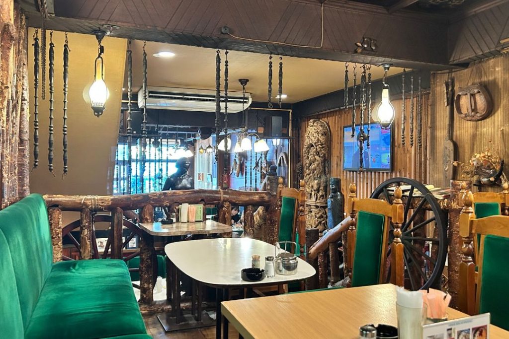 喫茶エーデルワイスの店内。緑の椅子や木の装飾、吊り下げ照明が並ぶ、昭和レトロな雰囲気の喫茶空間。