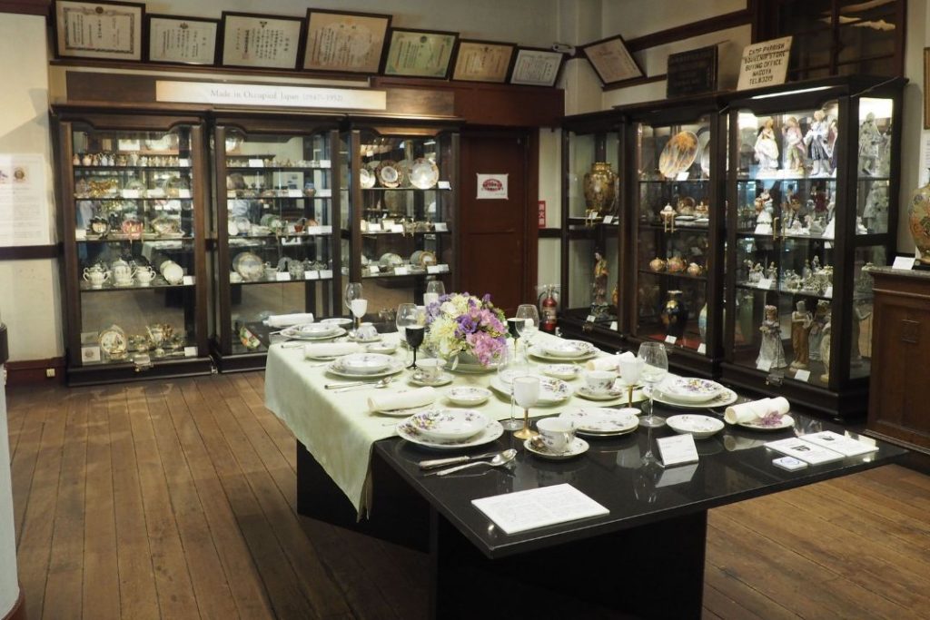 名古屋陶磁器会館の展示室に並ぶ陶磁器。食器が並んだテーブルやガラスケース、木の床が写る落ち着いた展示空間。