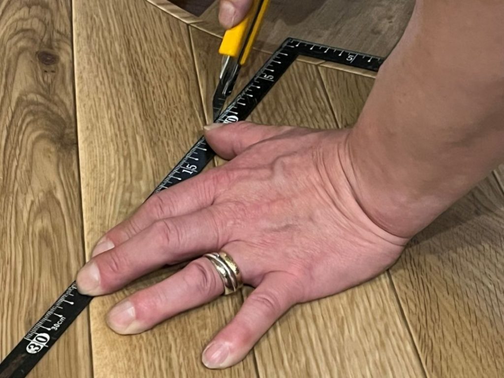 差し金を使ってペットマットをカッターで直角にカットする様子
