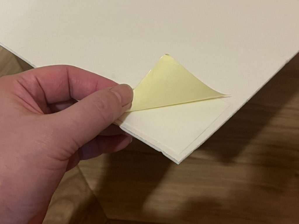 ペットマット裏面に貼った吸着滑り止めシートのはくり紙をめくる様子