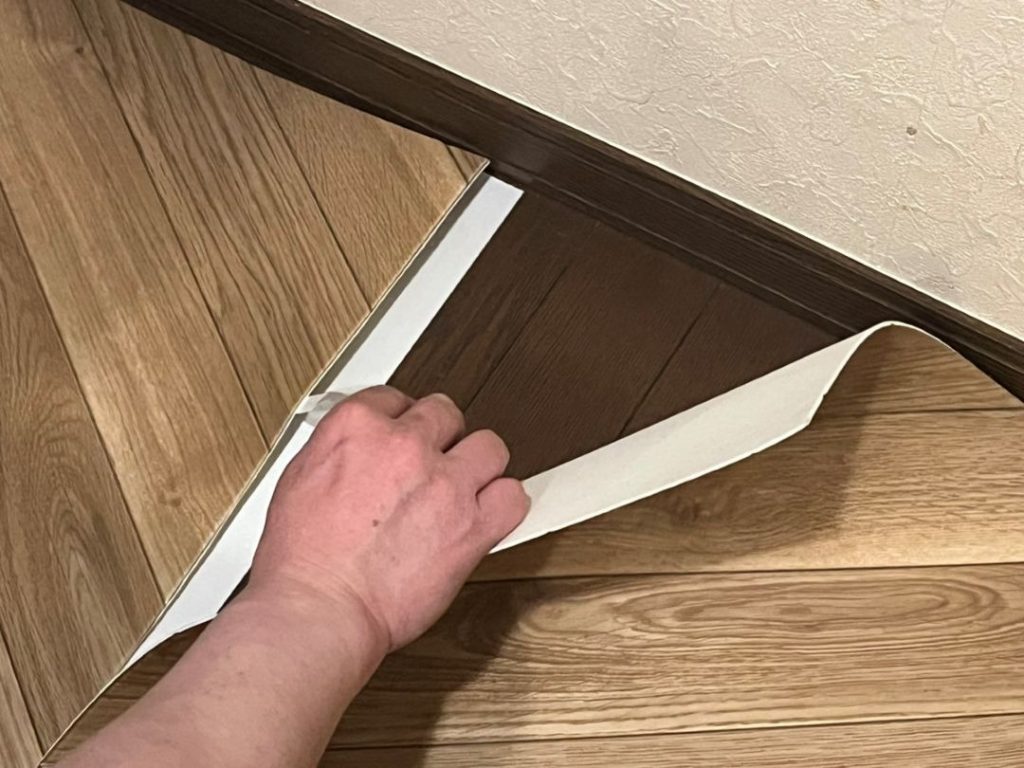 吸着滑り止めテープのはくり紙を剥がしながらペットマットを貼り合わせる様子