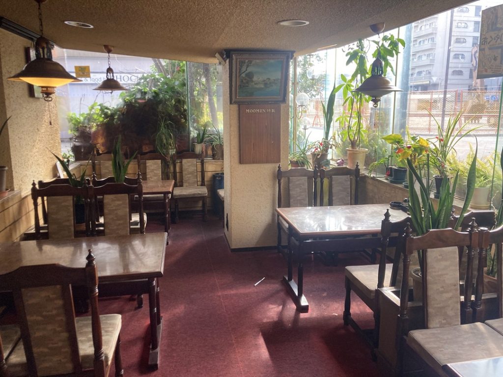 パーラームーミンの半地下席。窓辺の植物と赤い床が印象的な店内